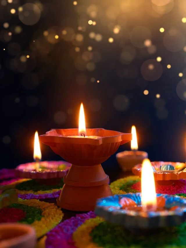 Diya lamps lit on colorful rangoli during diwali celebration